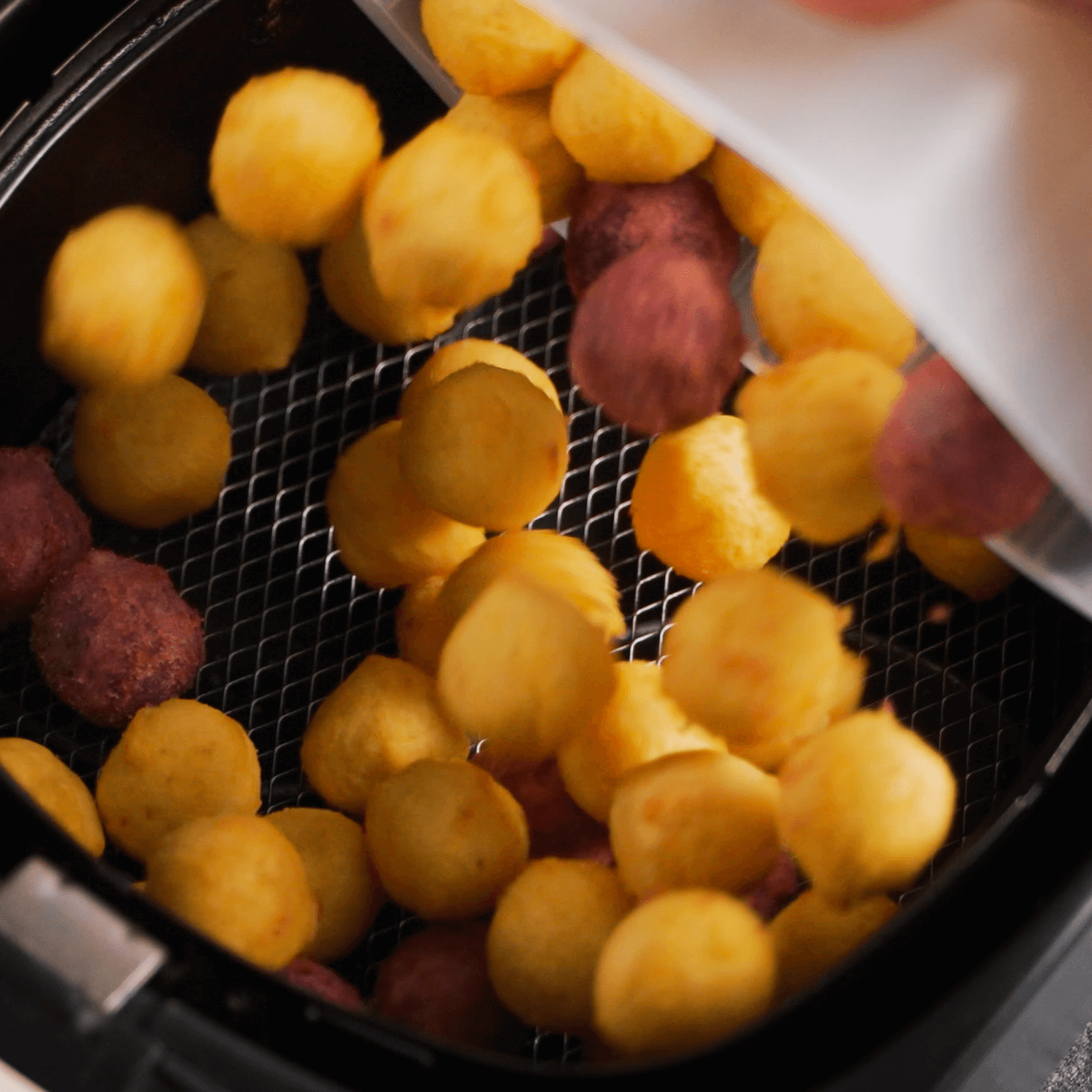 Lumo sweet potato balls poured into air fryer basket for cooking