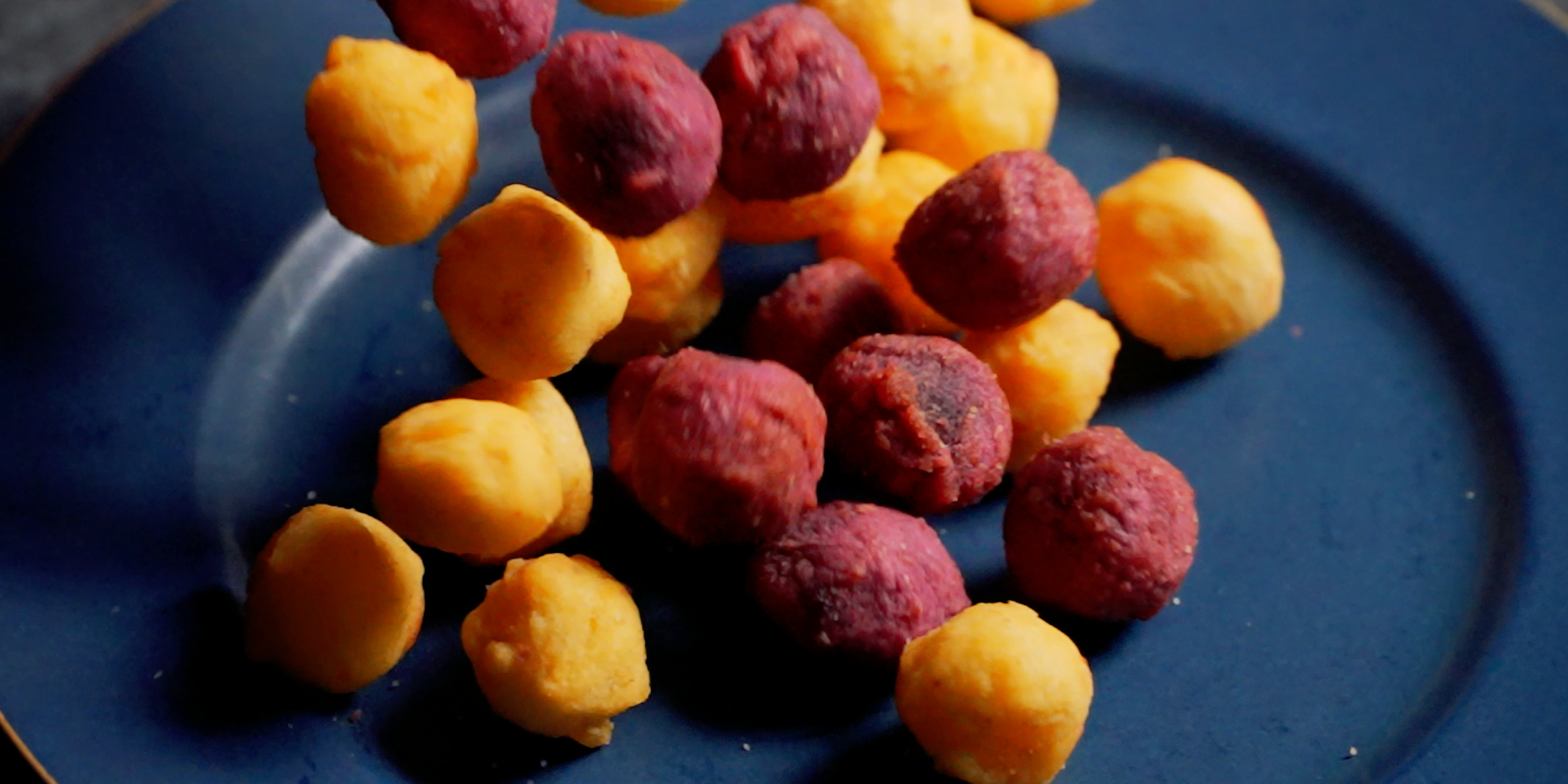 Golden and purple Lumo sweet potato balls served on a dark blue plate